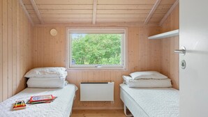 A small, wooden cabin room with two beds, a window, and a radiator. - Gorgeous home in Slagelse with WiFi (Slagelse)