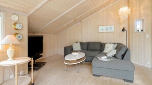 A cozy living room with a grey sofa, a small round table, a TV, and wooden walls. - Gorgeous home in Slagelse with WiFi (Slagelse)