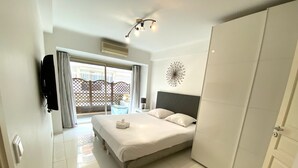 Habitación de hotel con cama, armario, televisión y vistas al exterior.