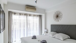 Un dormitorio moderno con una cama grande, cabecera, mesita de noche con lámpara y un adorno en la pared.