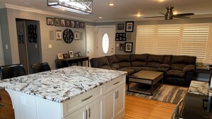 Ein modernes Wohnzimmer mit Ecksofa, Kücheninsel und Essbereich.