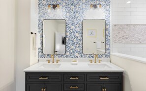 A bathroom with two sinks, black cabinets, and a blue leaf-patterned wall.