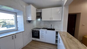Cocina moderna con armarios blancos, horno integrado y ventana con vistas panorámicas.
