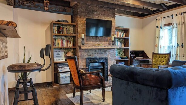 Ein gemütliches Wohnzimmer mit Kamin, Bücherregalen, einem Fernseher und bequemen Sitzgelegenheiten.