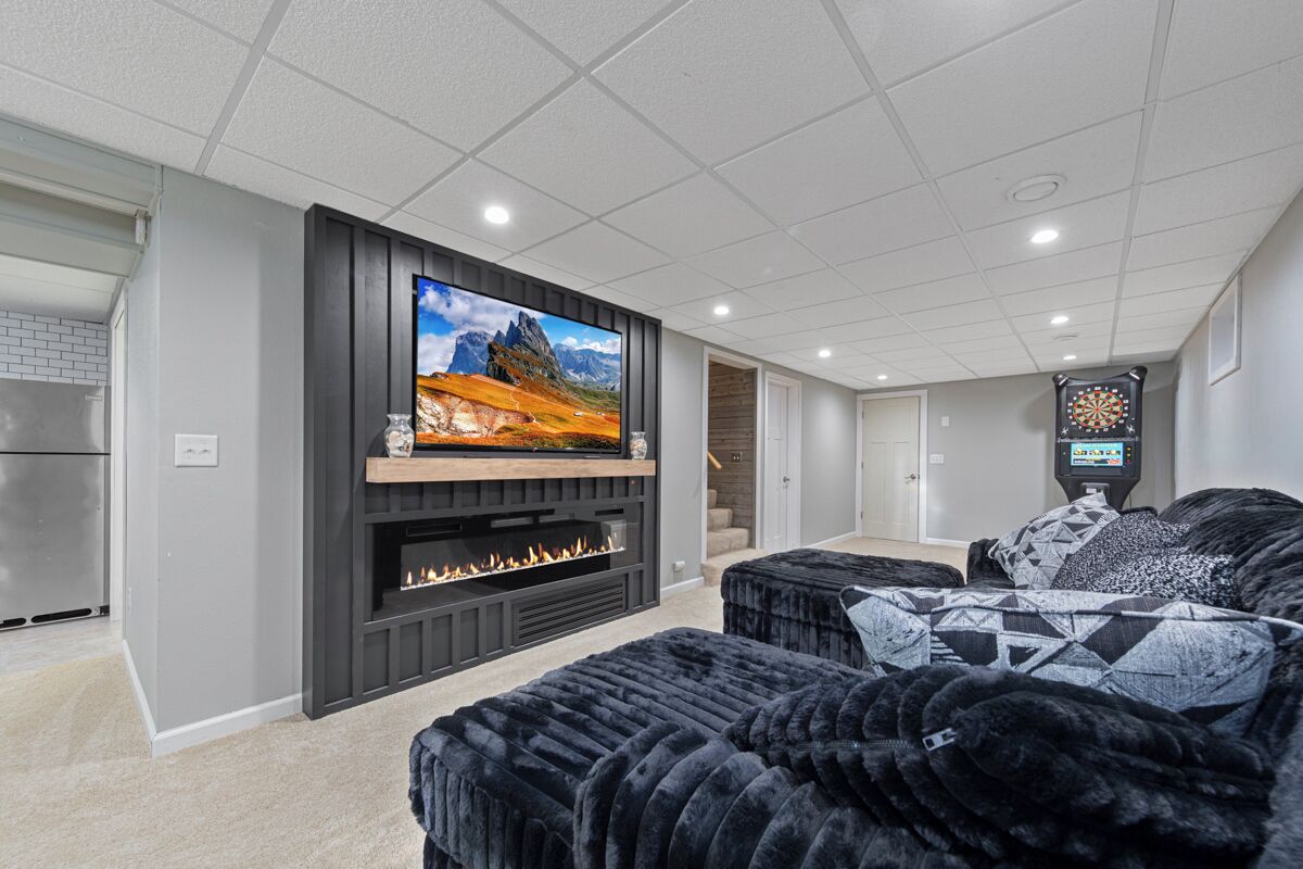 Una sala moderna con un televisor de pantalla plana grande, una chimenea y un dardo.