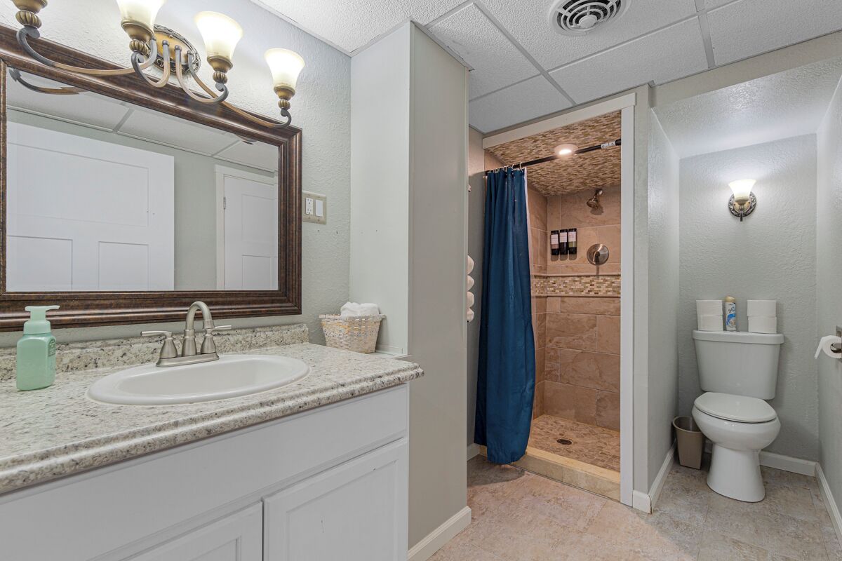Un baño con lavamanos, espejo, ducha e inodoro.