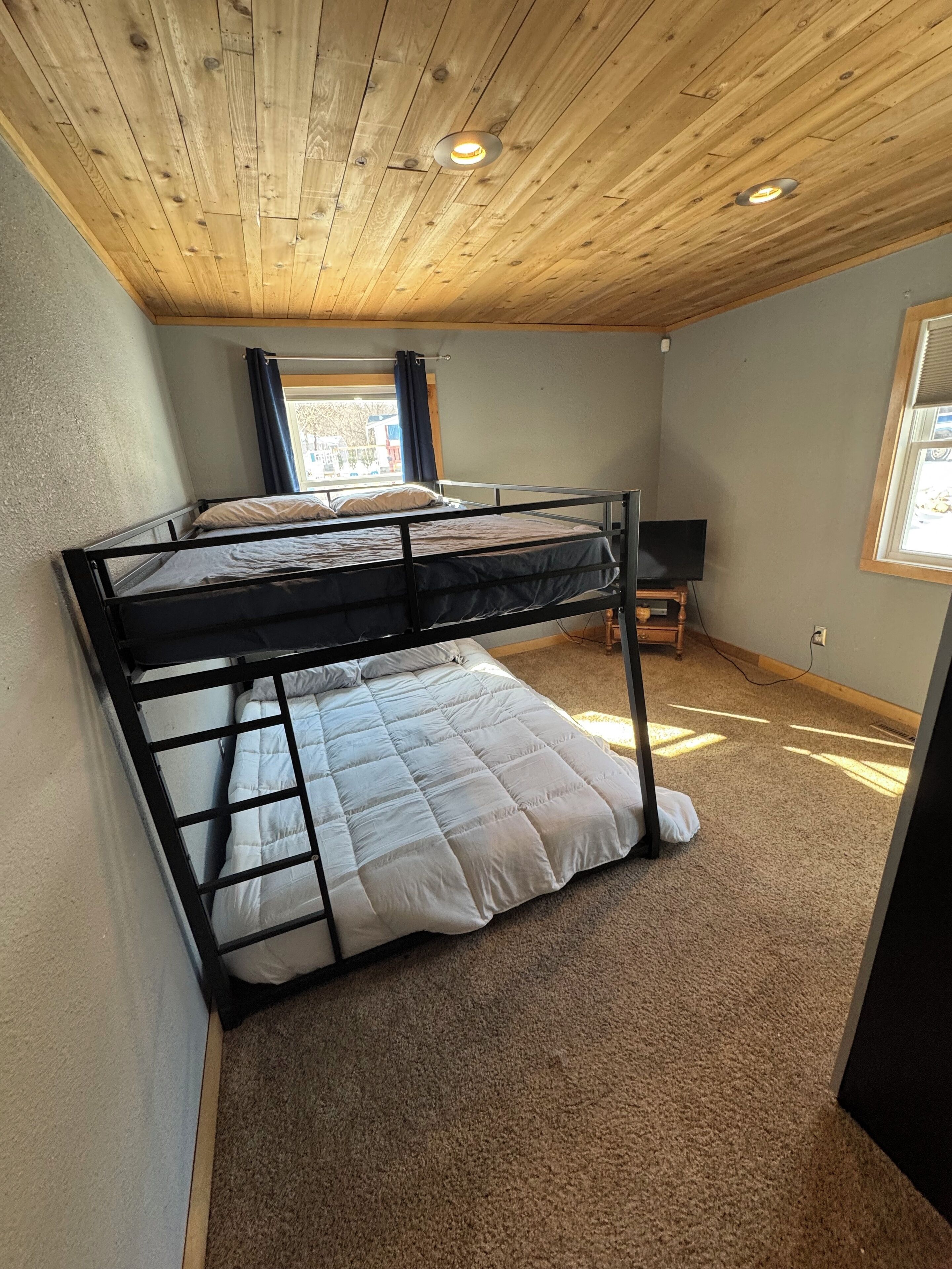 Ein Zimmer mit Etagenbett, Schreibtisch und Fenster.
