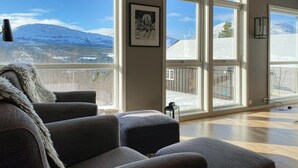 A cozy living room with a large window overlooking a snowy mountain landscape.