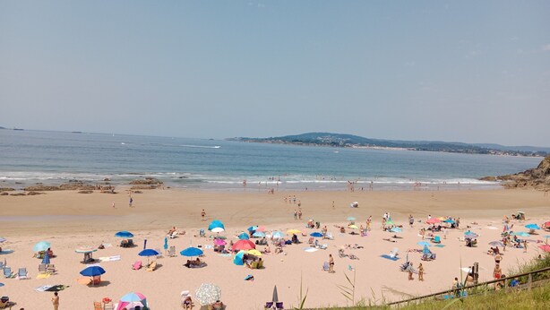 Een strand met veel parasols en mensen.
