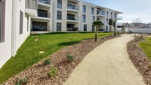 A modern multi-story residential building with balconies, a well-maintained lawn, and a gravel pathway. - Amazing apartment in La Tremblade with WiFi (La Tremblade)