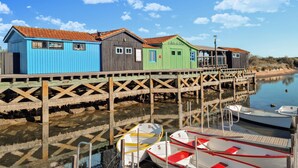 A wooden pier with colorful wooden buildings, boats docked at the end, and calm water reflecting the structures. - Amazing apartment in La Tremblade with WiFi (La Tremblade)