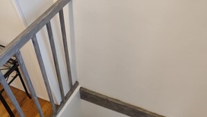 Una escalera de madera con barandilla metálica y pared blanca.