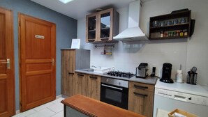 Una cocina compacta con gabinetes de madera, estufa a gas, lavavajillas y cafetera.