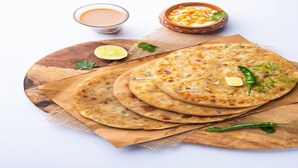 A stack of flatbreads on a wooden board with a bowl of sauce and a bowl of corn. - Hotel Srideep by stayeasy (Kolkata)