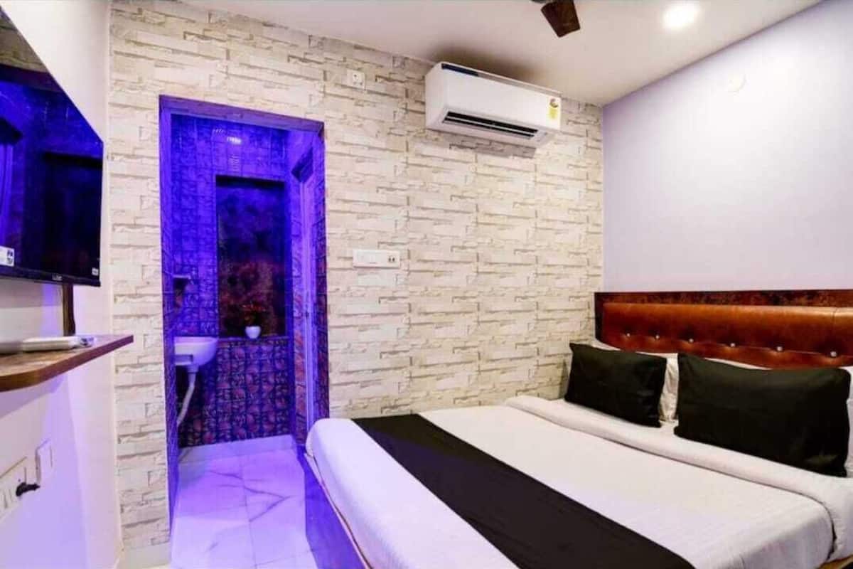 Un dormitorio con cama, cabecero, aire acondicionado de pared y baño con ducha.