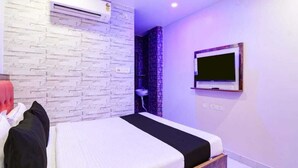 A hotel room with a bed, a TV mounted on the wall, and a brick-patterned wall.