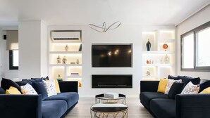 Ein modernes Wohnzimmer mit zwei Sofas, einem Couchtisch, einem Fernseher und Einbauschränken mit Dekorationselementen.