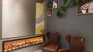 A modern interior with a fireplace, two leather chairs, and abstract wall art.