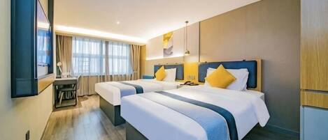 A hotel room with two beds, a desk, and a large window.