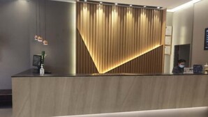 A modern reception desk with a wooden finish and a vertical light strip.