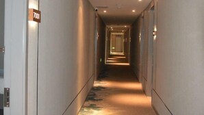 A hallway with a carpeted floor and a sign indicating room number 7001.
