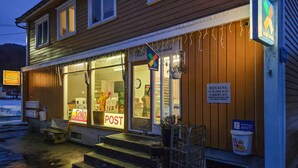 A building with a wooden facade, a Coca-Cola sign, and a 'Post' sign. - 1 bedroom nice apartment in Kvås (Kvås)