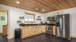 Una cocina moderna con armarios de madera, un refrigerador de acero inoxidable, un microondas y un fregadero.