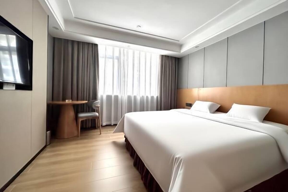 A modern hotel room with a large bed, a desk, and a chair.