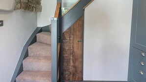 Una escalera con peldaños alfombrados, una puerta de madera y un muro decorativo de piedra.
