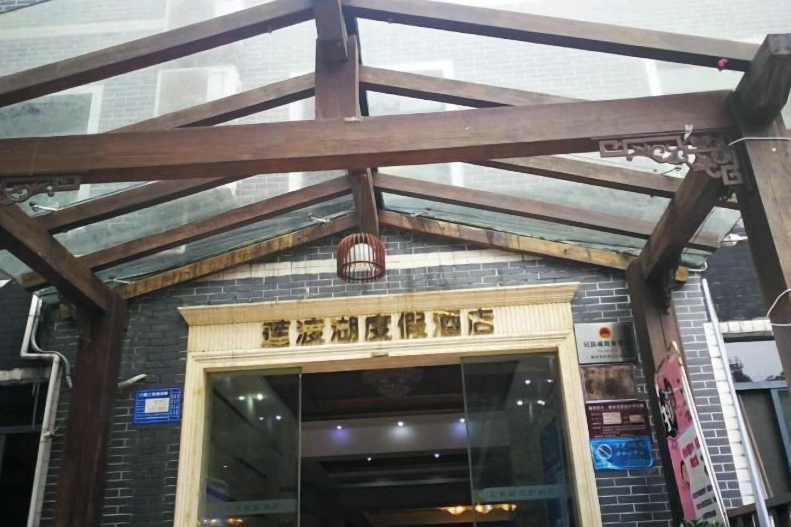 A hotel entrance with a glass facade, wooden beams, and a sign above the door.