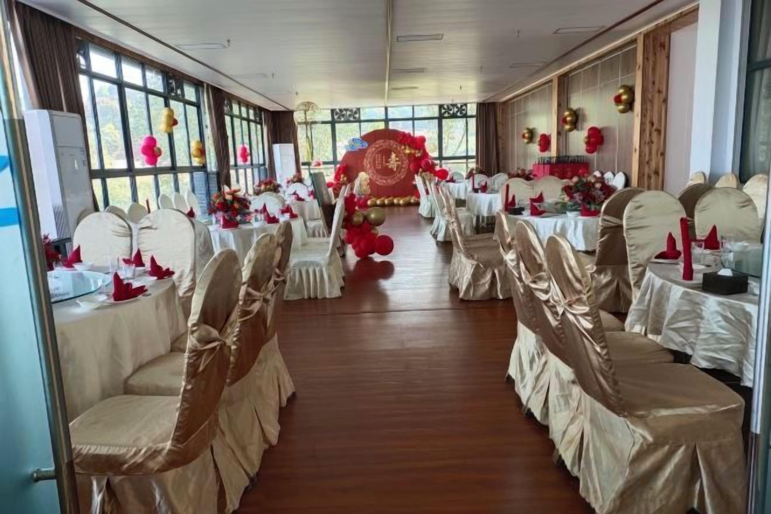 Una sala de banquet amb files de taules i cadires, grans finestres i un passadís central.