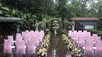 An outdoor wedding venue with rows of chairs and a floral archway.