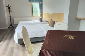 Une chambre d’hôtel avec deux lits, une tête de lit en bois, une fenêtre avec des rideaux et une chaise.