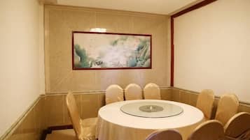 Een vergaderruimte met een ronde tafel en stoelen, een schilderij aan de muur en een betegelde vloer.