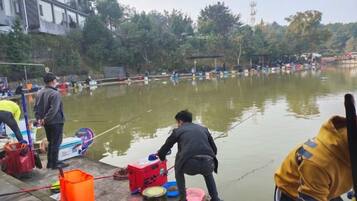 Un grupo de personas junto a un cuerpo de agua, algunas sosteniendo cañas de pescar.