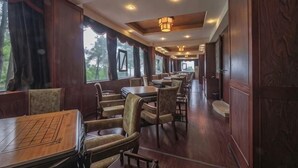 Un restaurante con mobiliario de madera, ventanas amplias e iluminación en el techo.