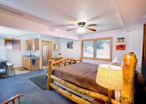 A compact room with a bed, a desk, a chair, and a window with blinds.