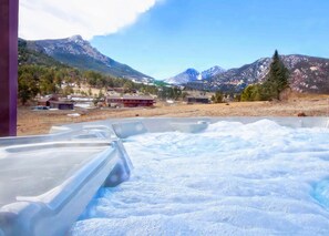 A hot tub area with a view of mountains and a small building in the background.