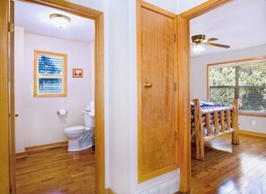 A bathroom with a toilet, a framed picture, and a window with blinds.