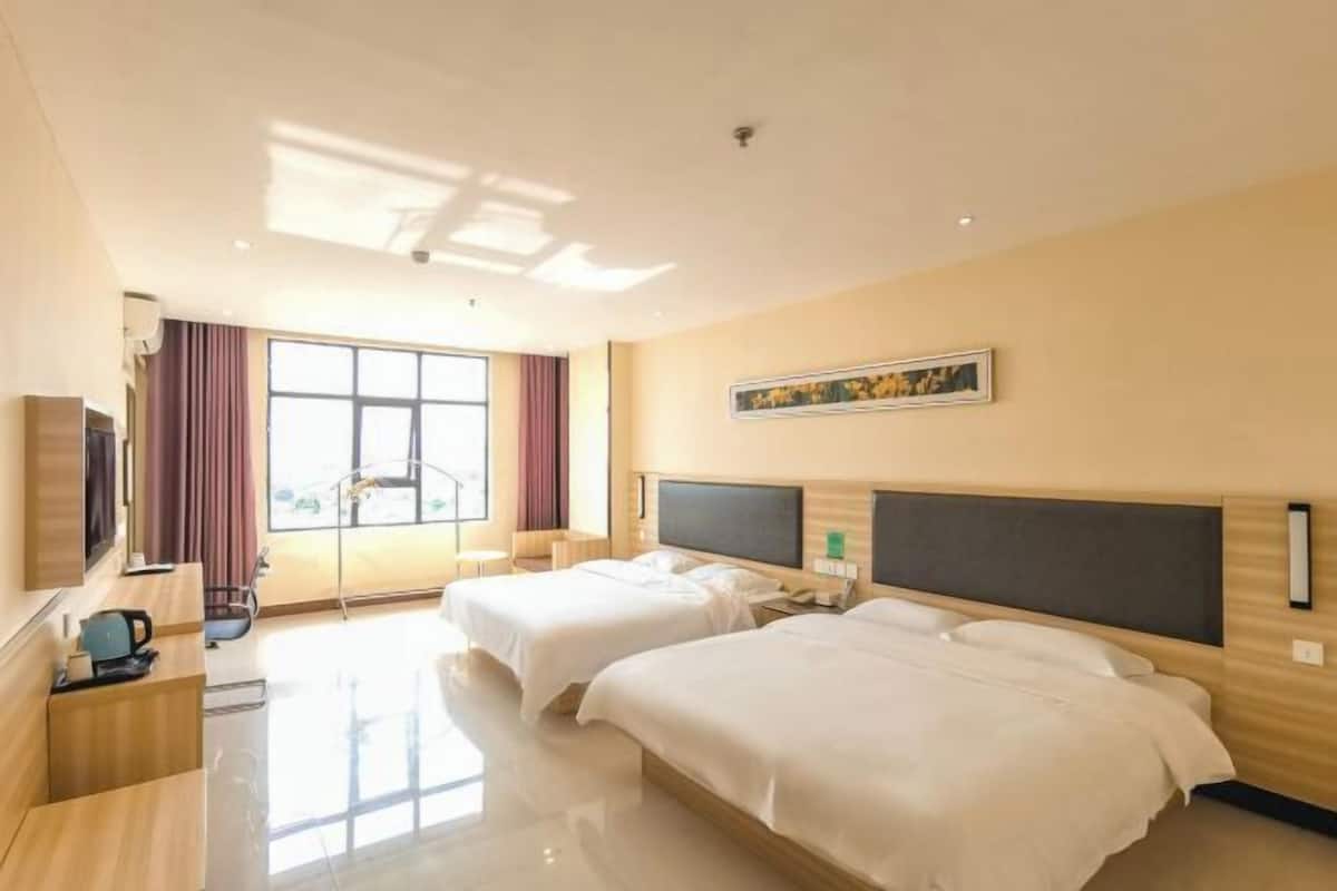 A hotel room with two beds, a desk, a TV, a window with curtains, and a painting on the wall.