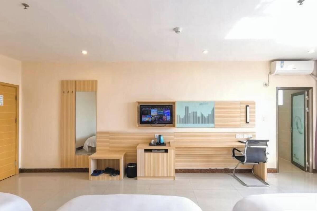 A hotel room with a bed, a desk, a chair, a television, and a wall-mounted artwork.