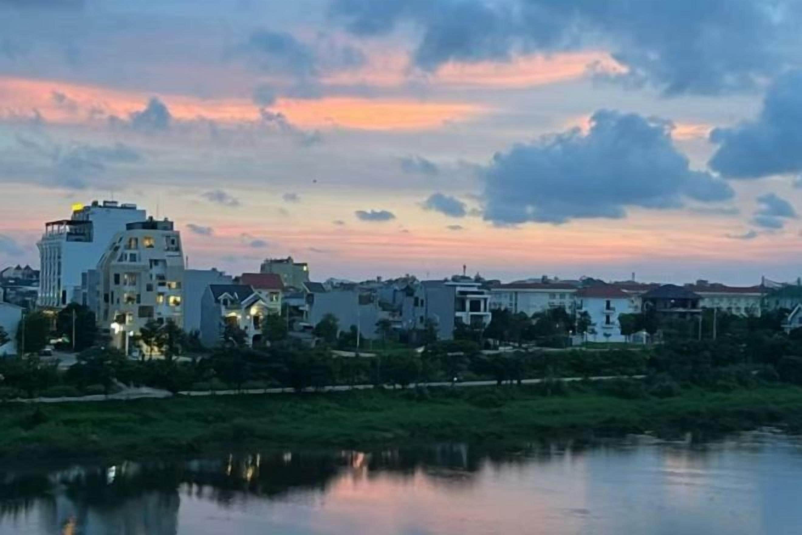 A cityscape with buildings along a waterfront during sunset.
