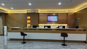 A reception area with a marble floor, two black bar stools, a reception desk, a flat-screen TV, and a wall-mounted information board. - Pinshang Express Chain Hotel (Dongxing Guomen Port) (Dongxing)