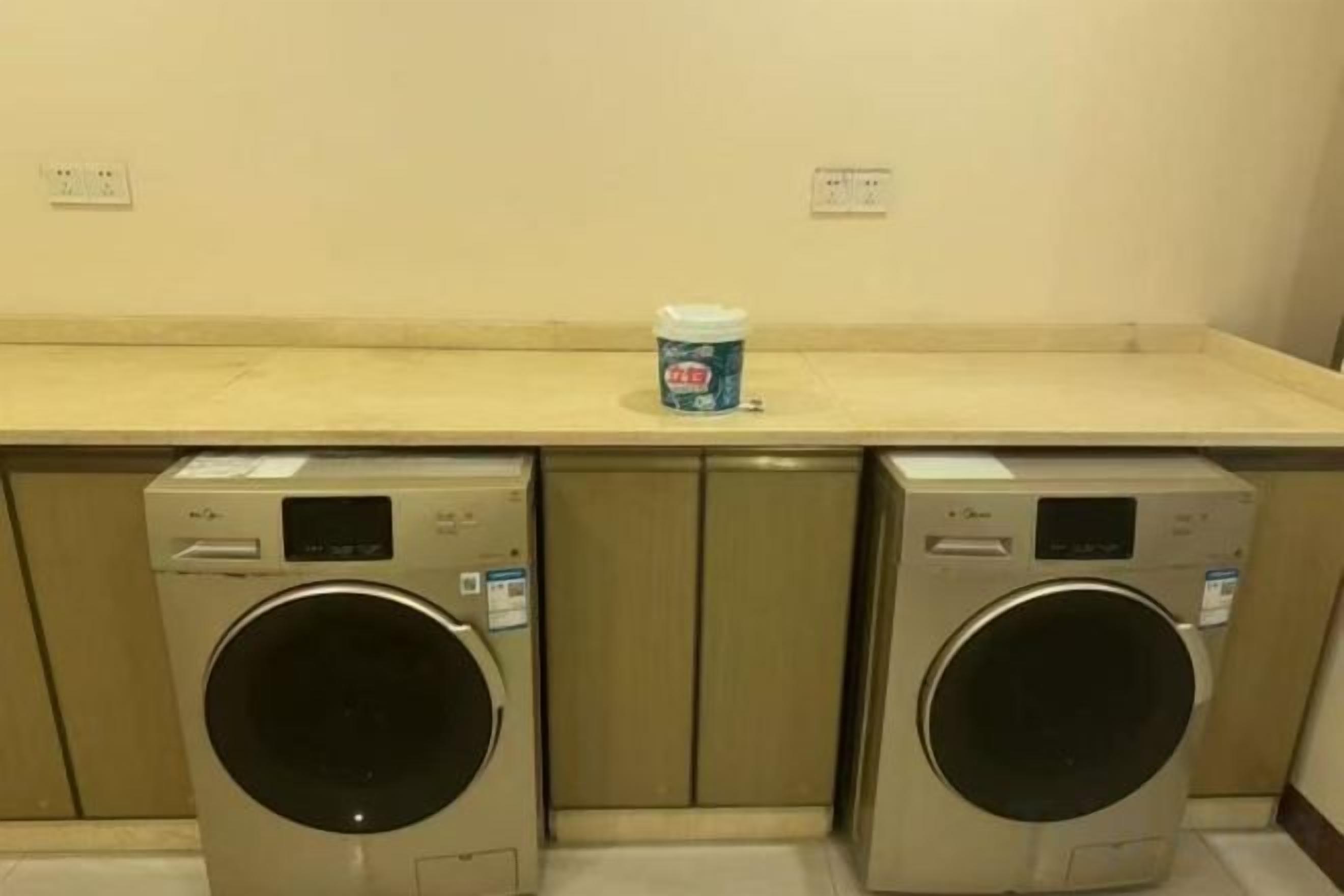 A laundry area with two front-loading washing machines and a detergent dispenser on the countertop.