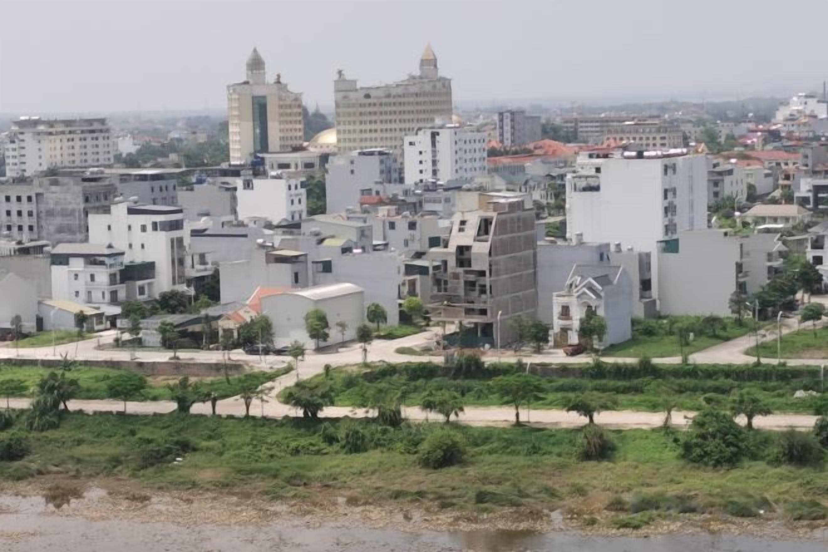 A cityscape with modern buildings, a river, and a park area.