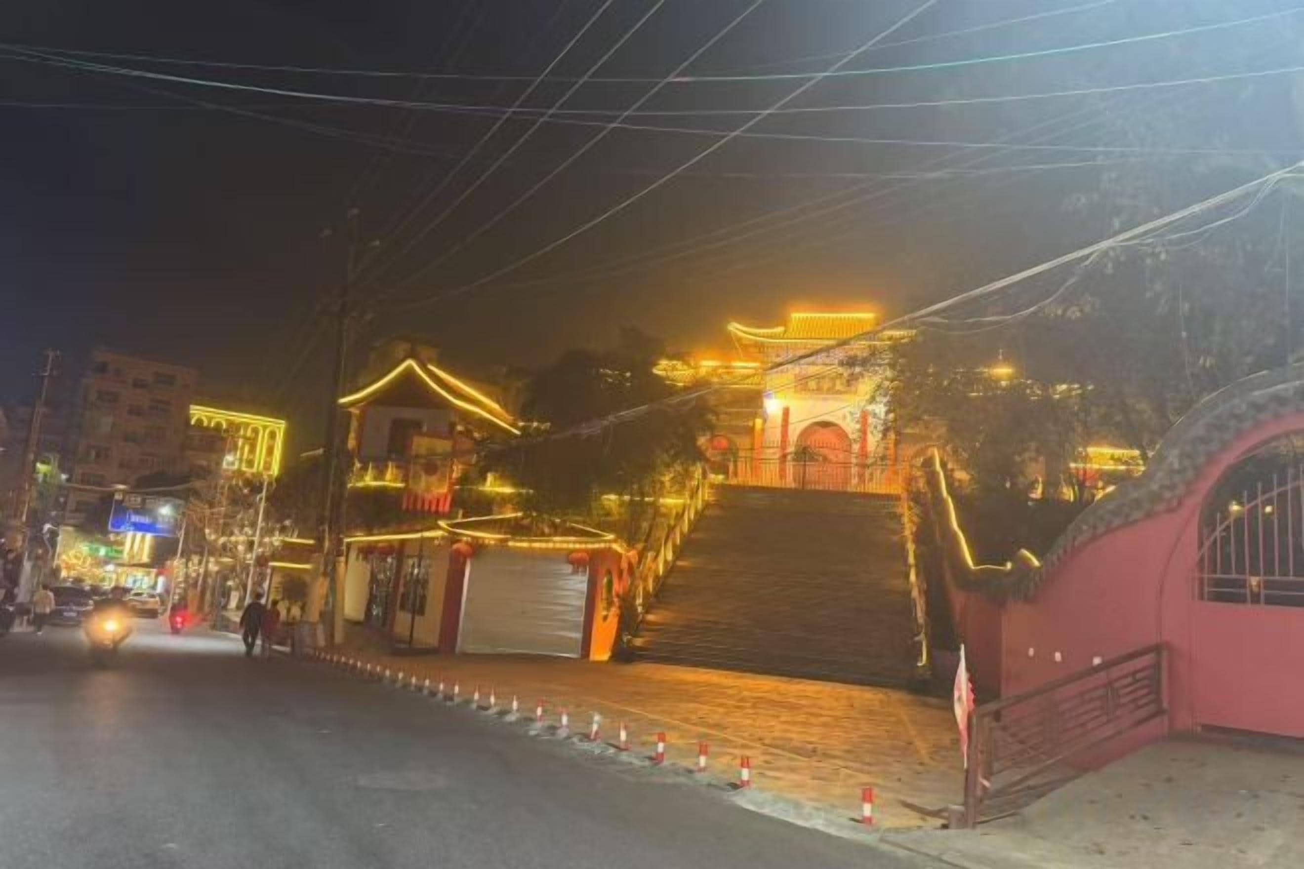 A building with a traditional architectural style, featuring a staircase leading to a gated entrance.