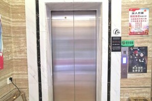 Een lift met een bedieningspaneel en een bordje met een brandmeldingsaanduiding.