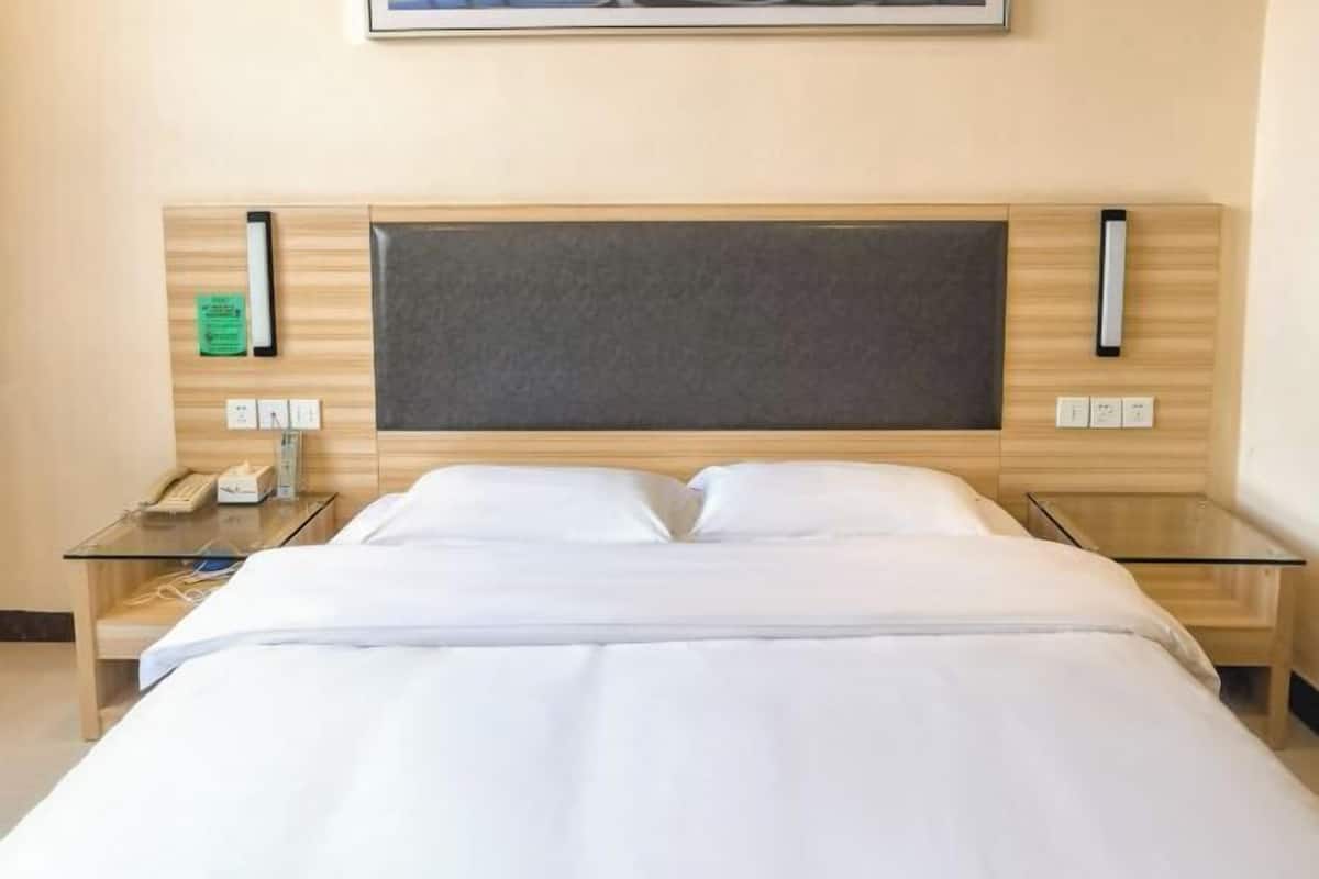 A hotel room with a bed, bedside tables, a telephone, and a framed picture on the wall.