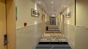 A hotel hallway with a tiled floor, a staircase, and framed artwork on the walls. - Pinshang Express Chain Hotel (Dongxing Guomen Port) (Dongxing)