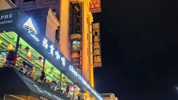 A brightly lit building with signage for 'PHÈ COFFEE' and 'CÔNG TY THƯƠNG NĂM TƯ'. - Pinshang Express Chain Hotel (Dongxing Guomen Port) (Dongxing)
